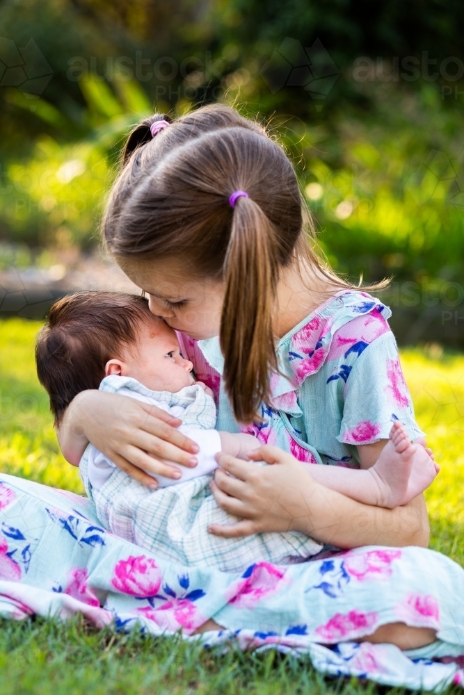 Image of Older child cuddling young baby girl outside - loving family ...