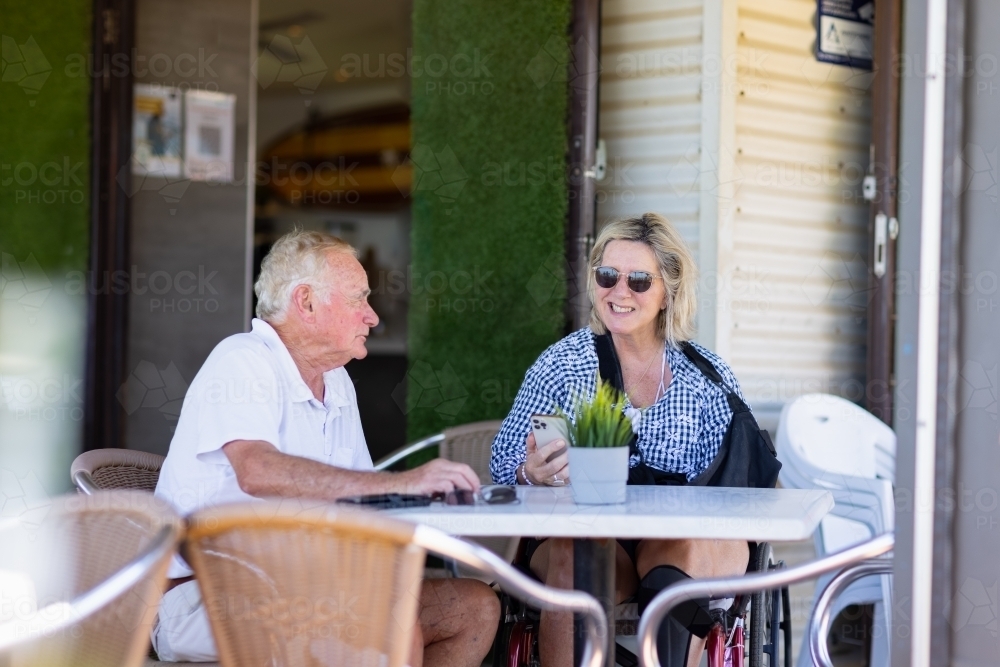older couple sitting at outside cafe table - Australian Stock Image