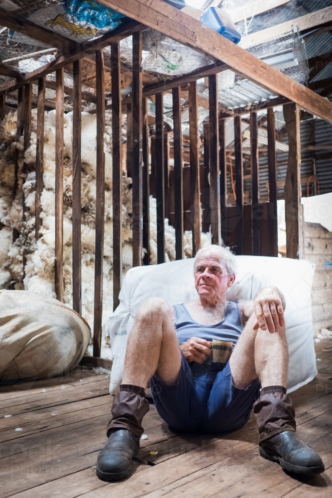 Older farmer having a tea break in the shearing shed. - Australian Stock Image