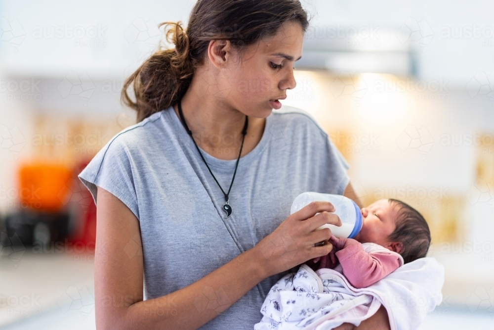 older girl bottle feeding her newborn baby sister : Austockphoto older girl bottle feeding her newborn baby sister - Australian Stock Image
