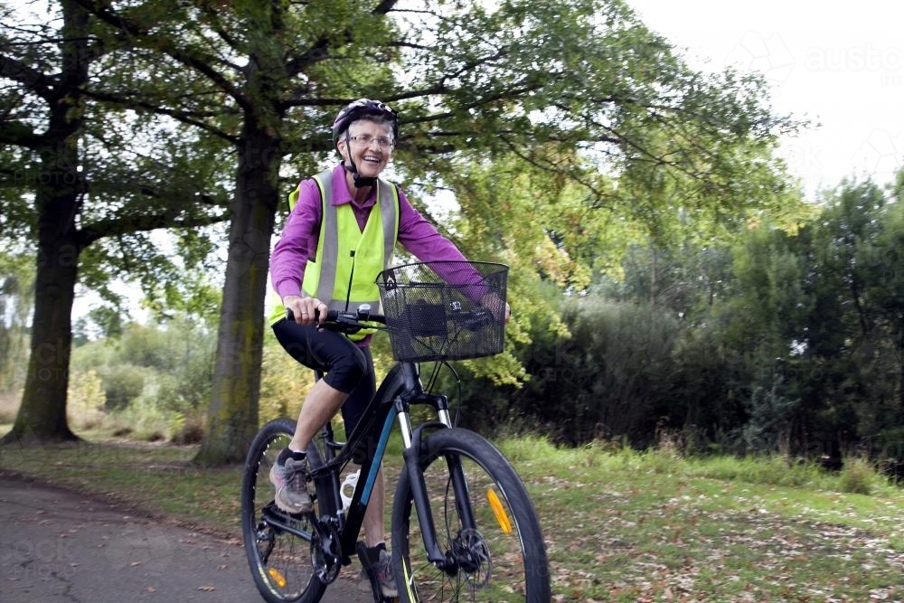 Older lady riding bike - Australian Stock Image