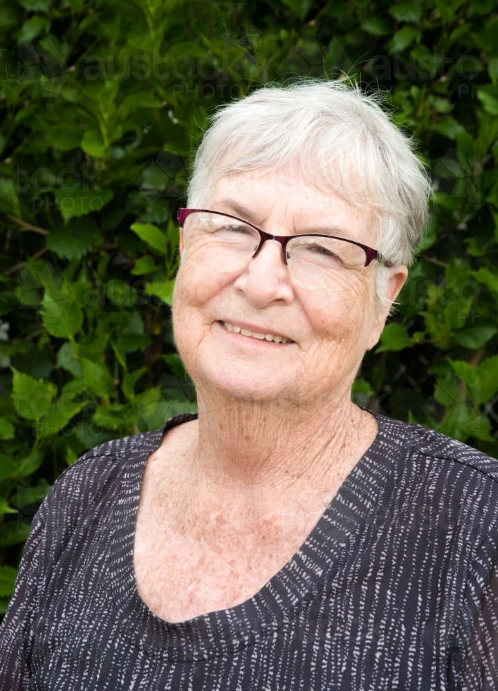 Older lady standing outdoors smiling. - Australian Stock Image