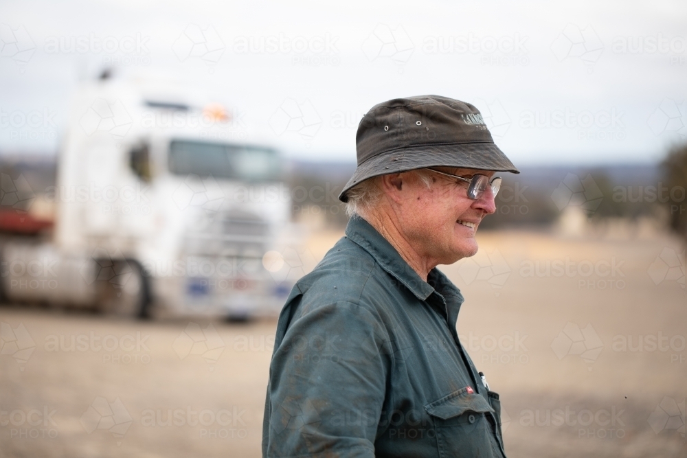 older man in workwear outdoors with prime mover in background - Australian Stock Image