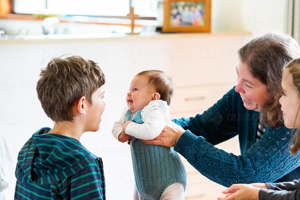 Older mum with three children playing together inside home - middle aged parent - Australian Stock Image