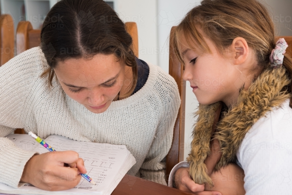 Older sister helping her younger sister with homework. - Australian Stock Image
