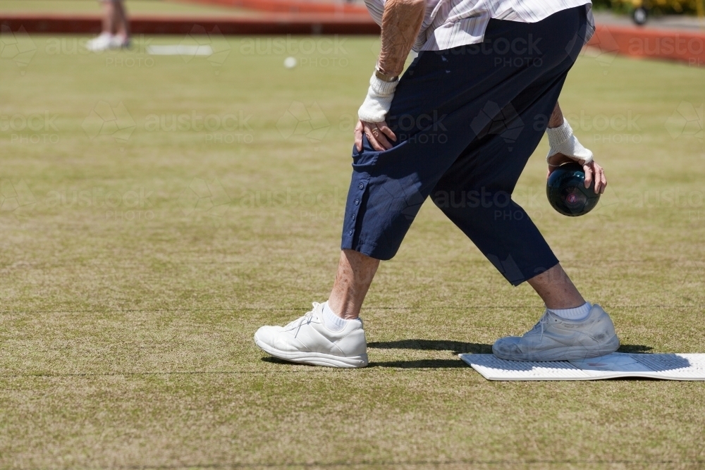 Older woman delivering a lawn bowl - Australian Stock Image