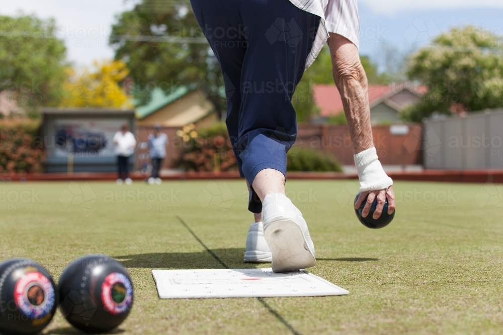 Older woman delivering a lawn bowl - Australian Stock Image