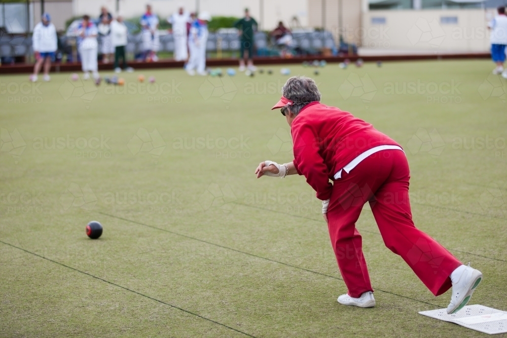 Older woman delivering a lawn bowl - Australian Stock Image