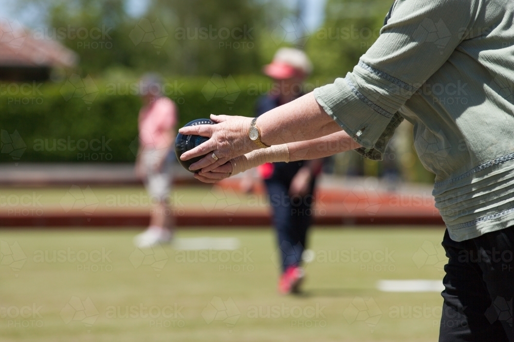Older woman lining up her lawn bowl - Australian Stock Image