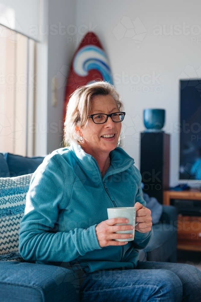 Older woman looking happy smiling with mug in hand - Australian Stock Image