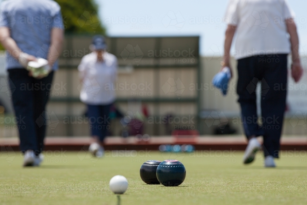 Older woman walking up and down the lawn bowls green - Australian Stock Image
