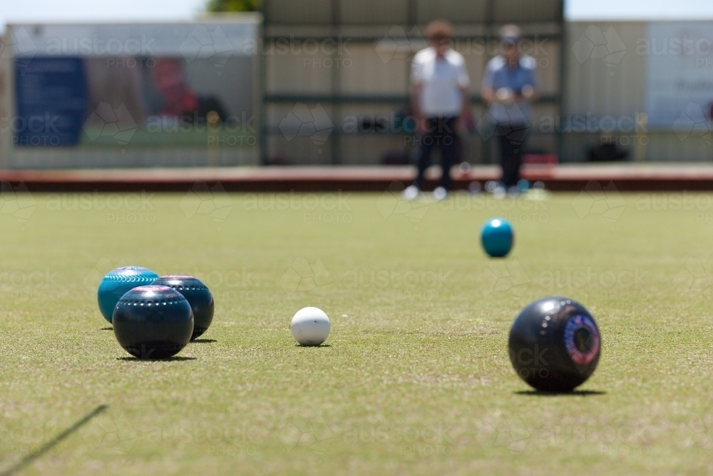older woman watching bowl rolling down the green - Australian Stock Image
