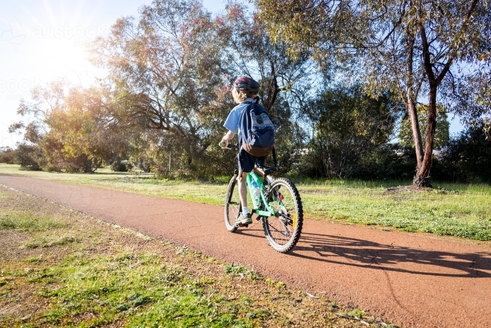 One child riding bike to school along path - Australian Stock Image
