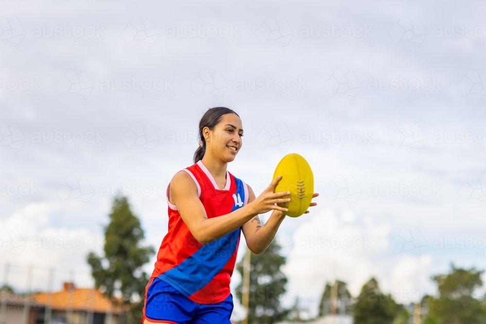 one female football player holding oval shaped aussie rules football - Australian Stock Image