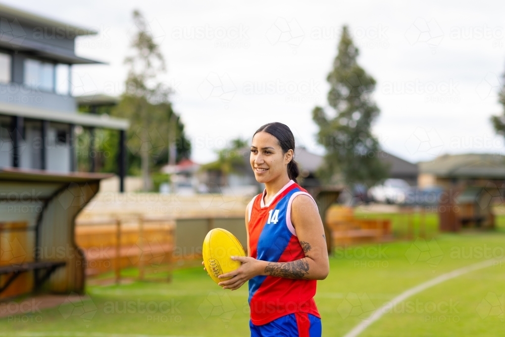 one female football player holding yellow football - Australian Stock Image