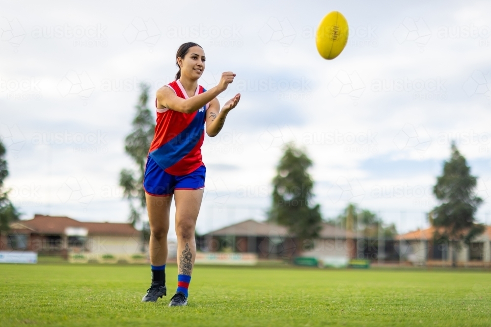 one female footballer handballing the ball at training - Australian Stock Image