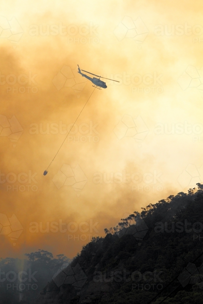 One fire fighting helicopter dumping water onto a bushfire on Maddens Plains, Illawarra, NSW - Australian Stock Image