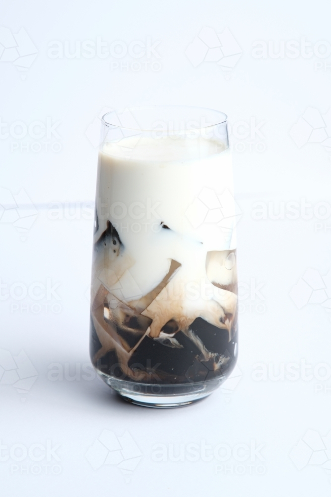 One refreshing ice-cold drink in a tall glass on a white counter - Australian Stock Image