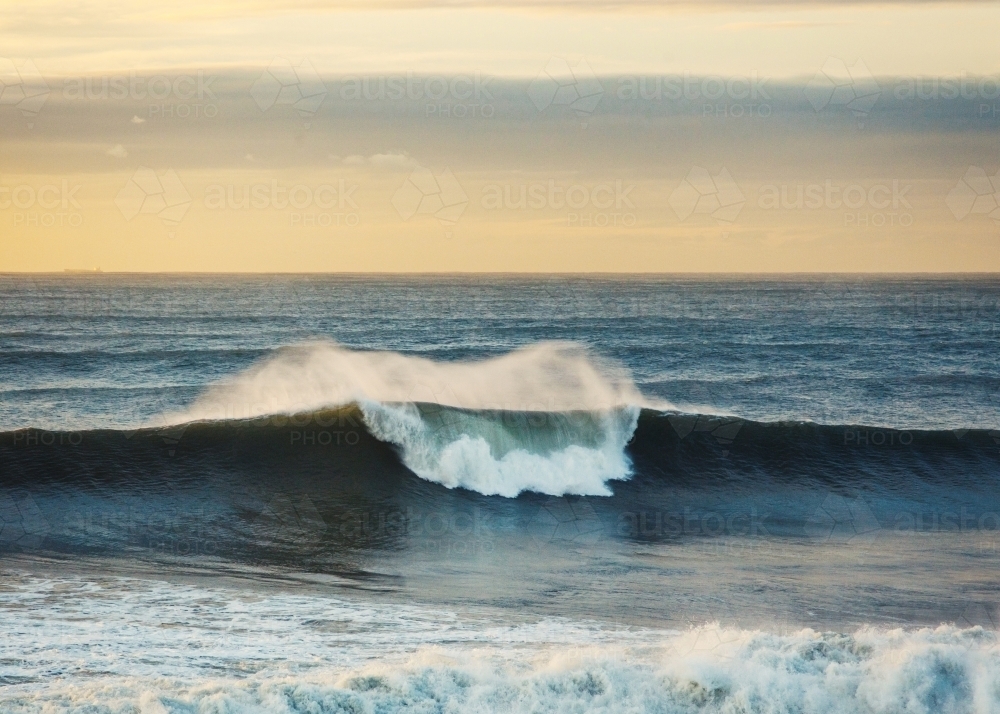 One wave breaking at the beach at sunrise - Australian Stock Image
