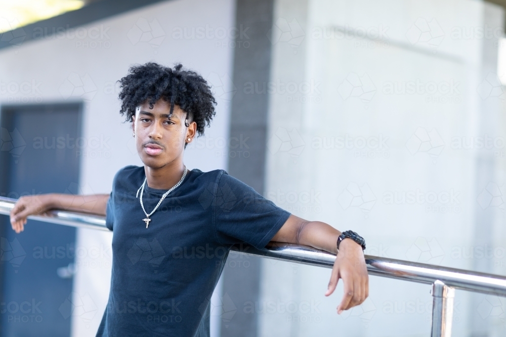 one young man in black tee leaning against railing - Australian Stock Image