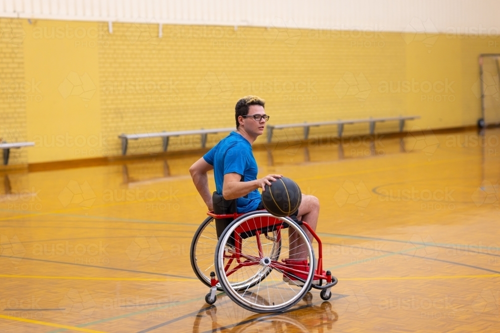 one young man on basketball court in wheelchair - Australian Stock Image