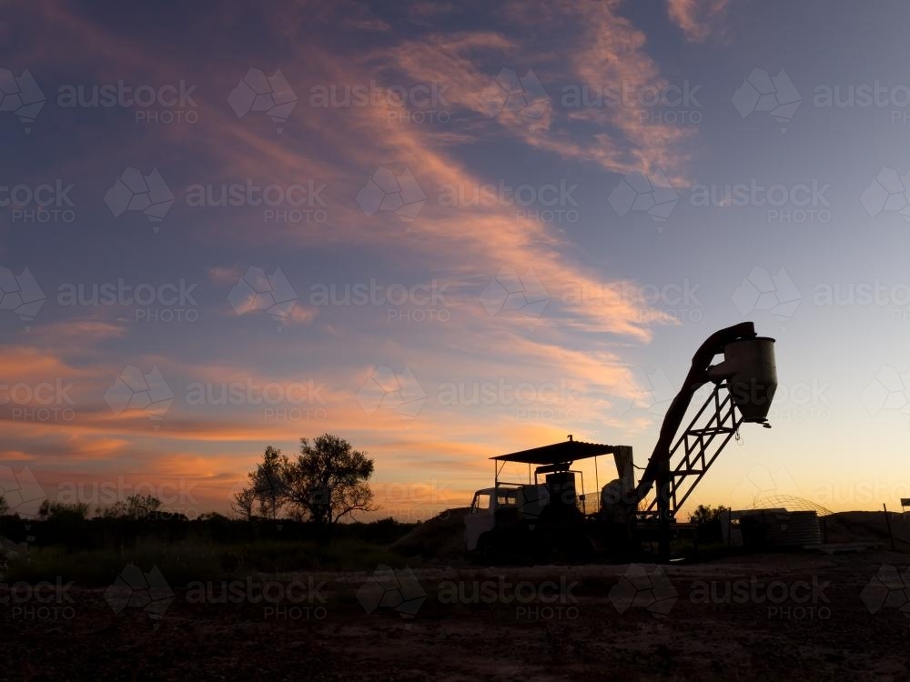 Opal extraction machinery silhouetted against sunset - Australian Stock Image