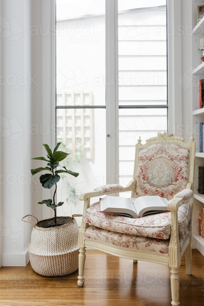 Open book on a comfortable vintage reading chair in a renovated home - Australian Stock Image