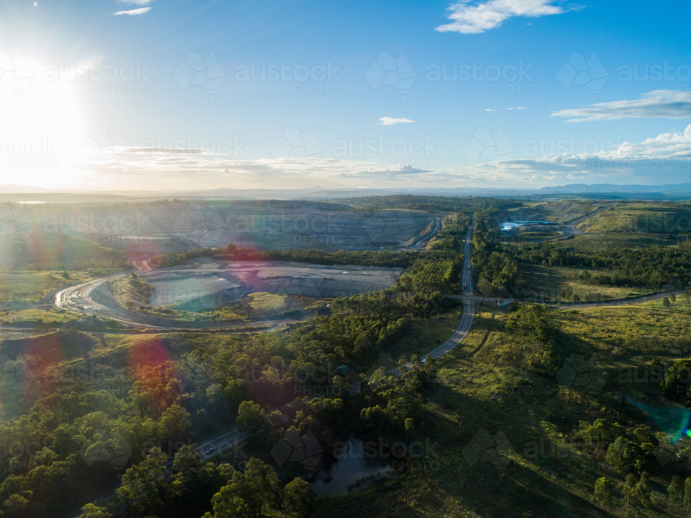Open cup coal mine in landscape with bright afternoon sunshine overhead - Australian Stock Image