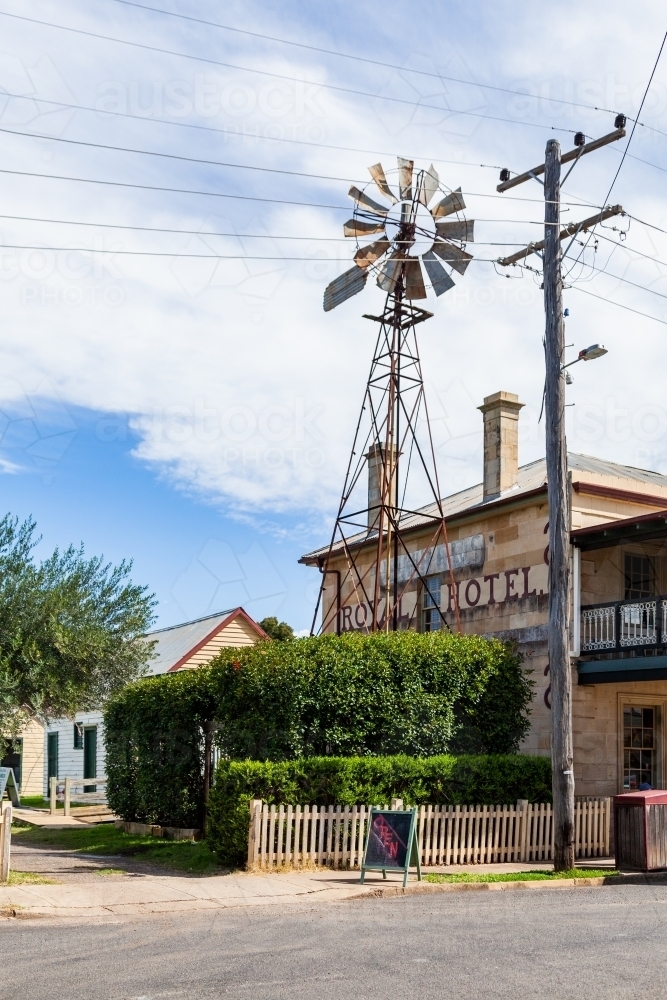 open sign outside a rural country pub on sunlit day with windmill - Australian Stock Image