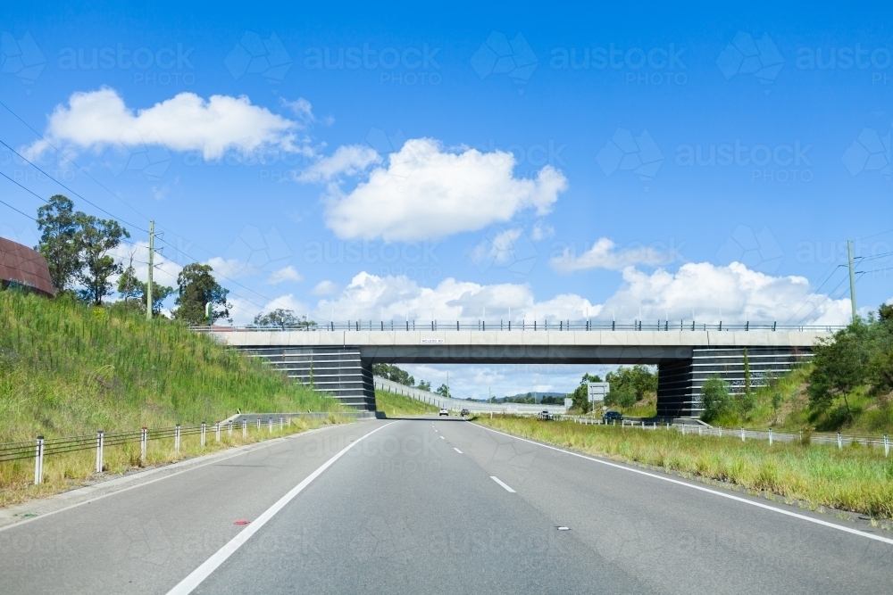 Open sunlit road with overpass on highway - Australian Stock Image