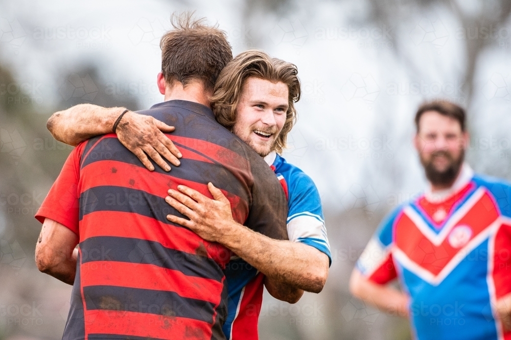 Opposing players hug after rugby union match - Australian Stock Image
