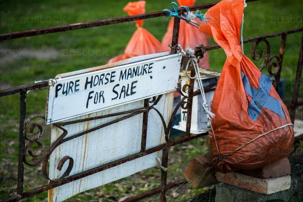 Orange bags of horse manure for sale on someones front lawn - Australian Stock Image