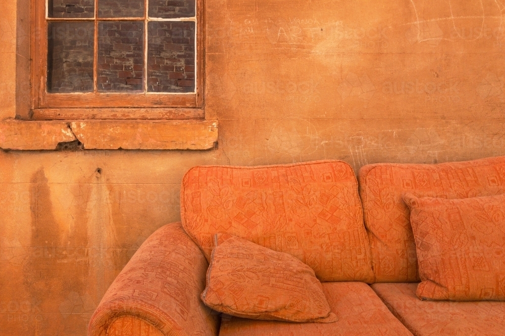 orange couch against old wall with copy space - Australian Stock Image