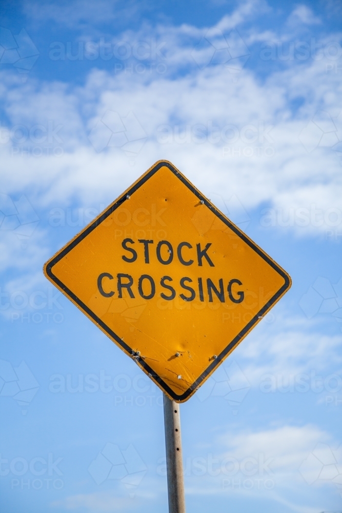 Orange diamond shaped stock crossing sign with blue sky behind - Australian Stock Image