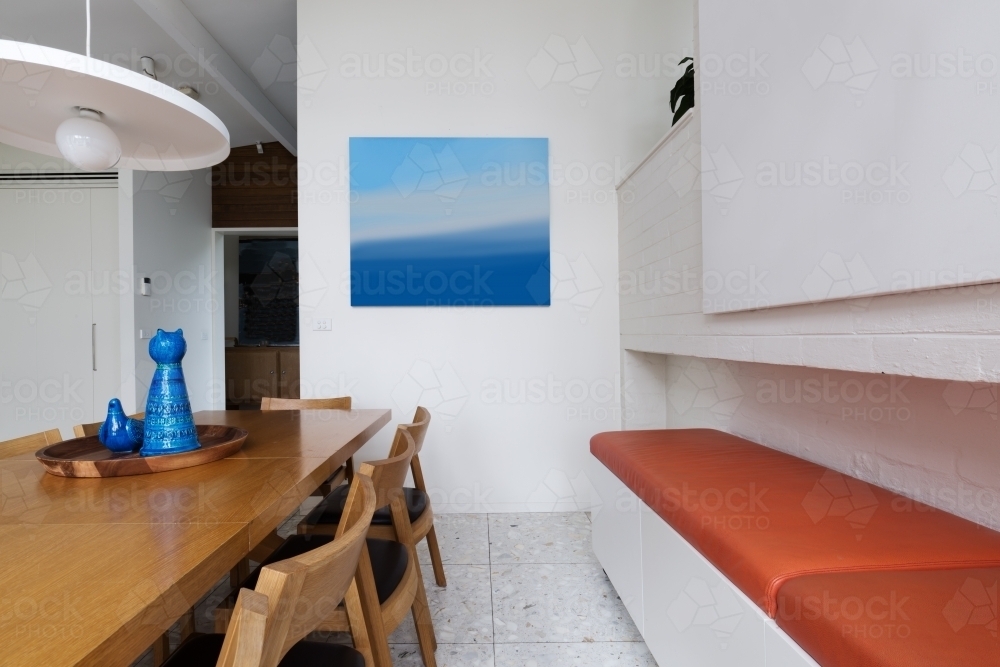 Orange leather bench seat along scandinavian styled dining room interior with blue accents - Australian Stock Image