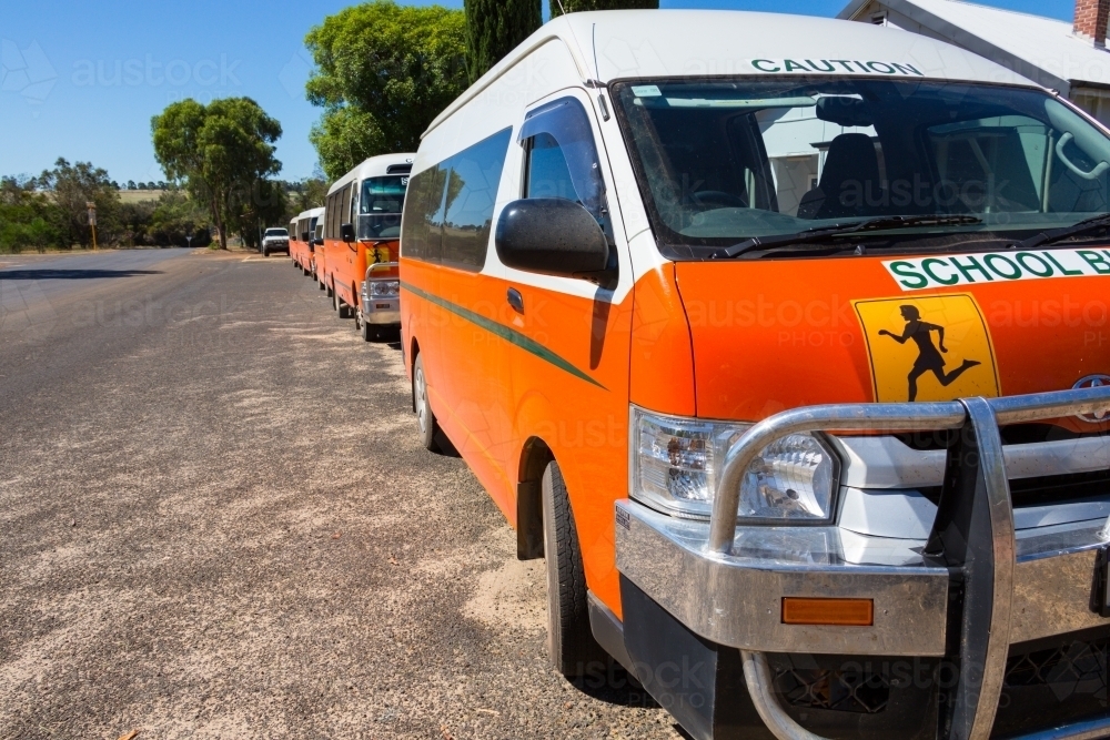 Orange school buses lined up outside a country school - Australian Stock Image