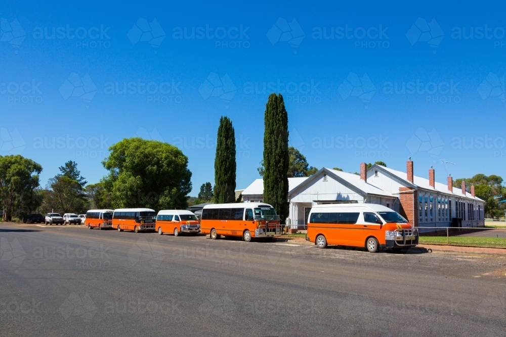 Orange school busses parked outside a small country school - Australian Stock Image