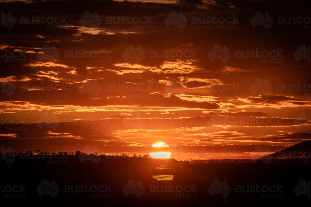 Orange sun setting over rural landscape - Australian Stock Image