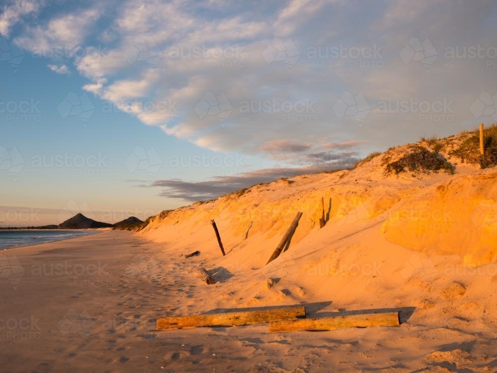 Orange sunlight on beach erosion caused by a big storm - Australian Stock Image