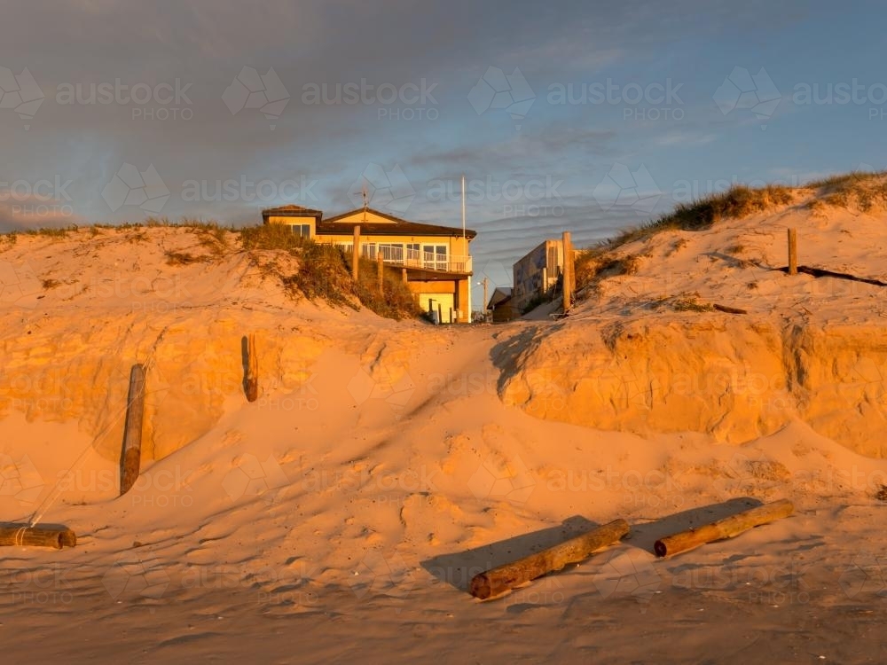 Orange sunlight on beach erosion caused by a big storm - Australian Stock Image