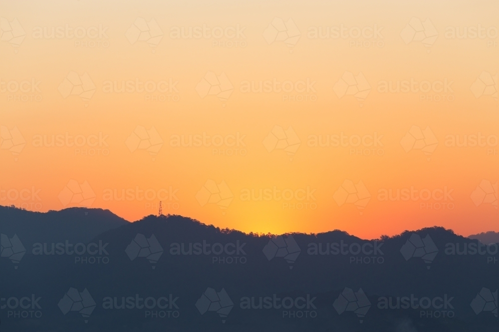 Orange sunset over distant rolling hills - Australian Stock Image