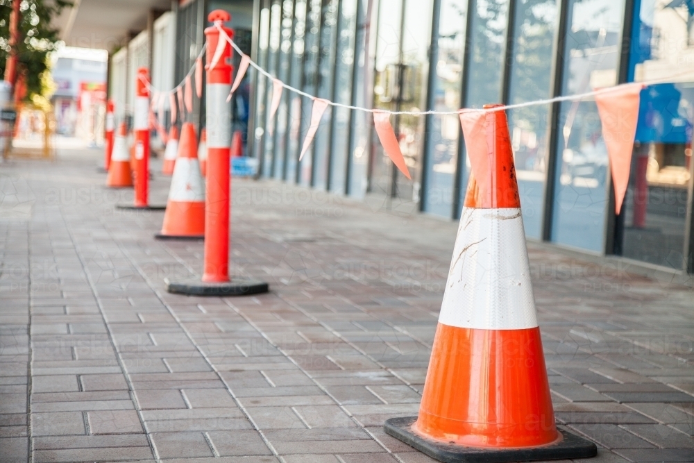 Orange traffic cones keeping pedestrians away from worksite on footpath - Australian Stock Image