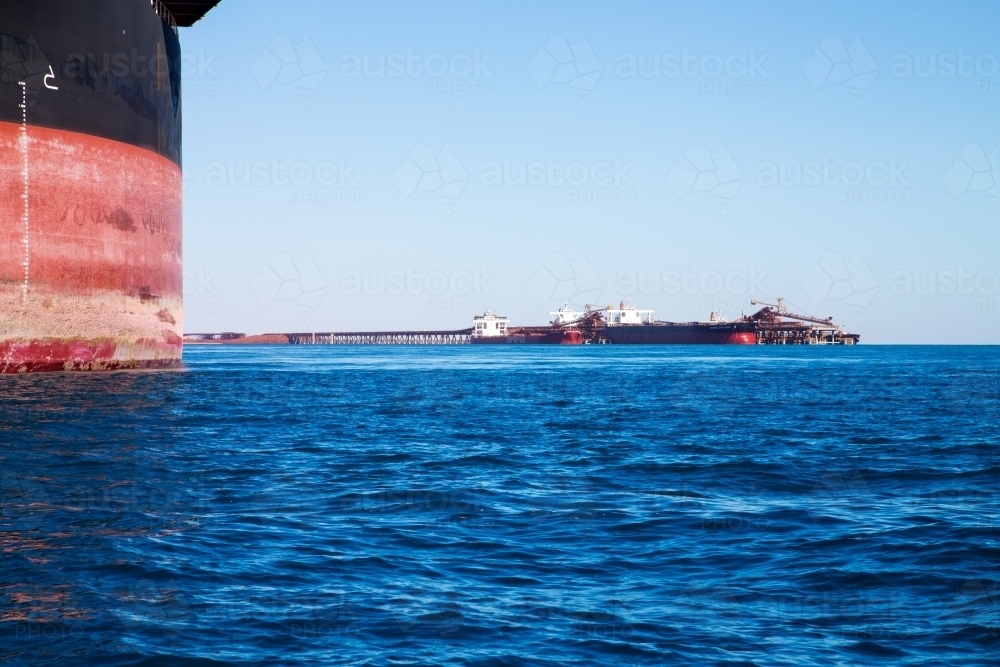 ore ship's hull with outloading and ships in distance - Australian Stock Image