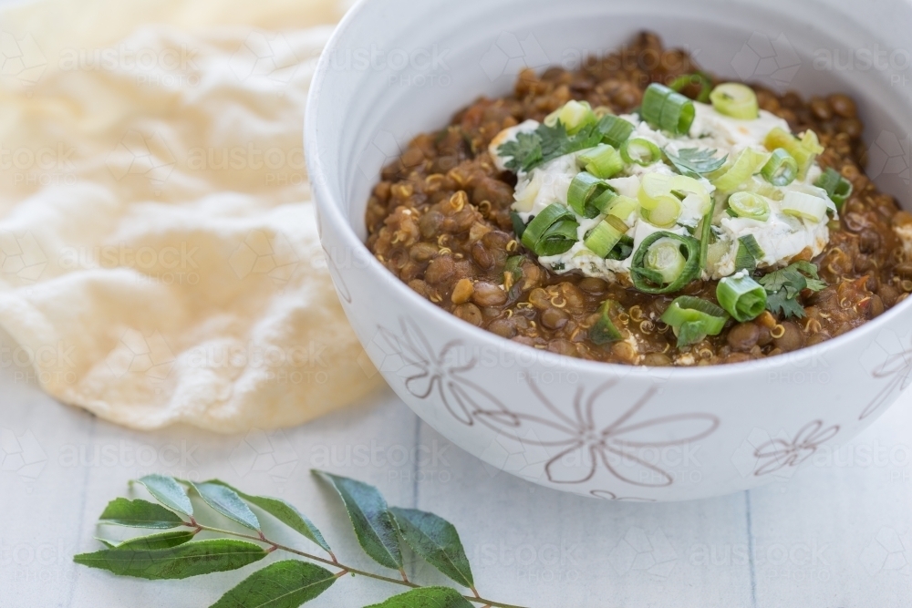 Organic Bowl of vegetarian Lentil Dahl with a papa-dum and lime leaves - Australian Stock Image