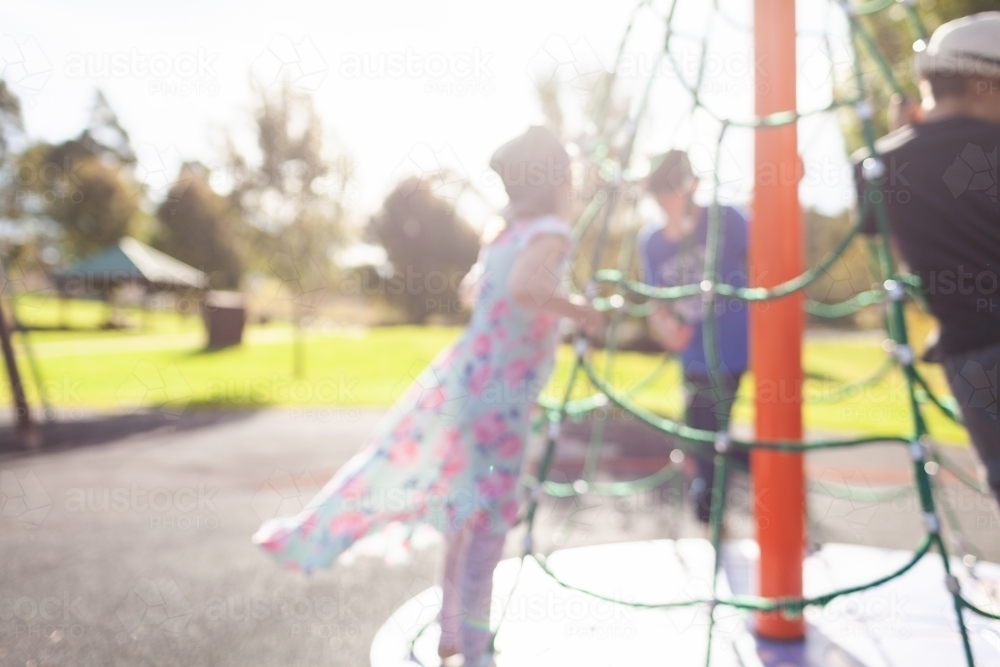 Out of focus children playing on spinning play equipment at park - Australian Stock Image