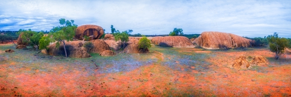 Outcrop of rock formations on red sand plains - Australian Stock Image