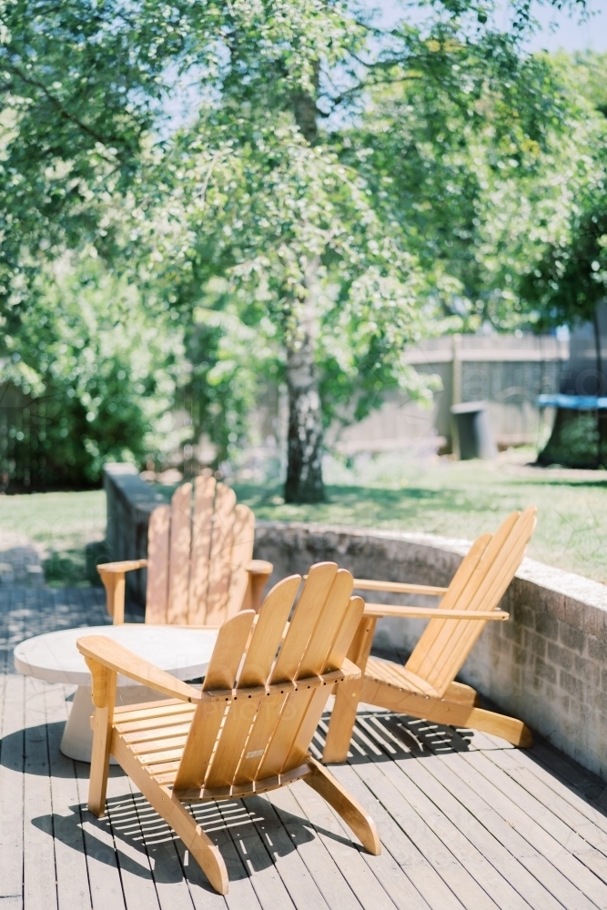 Outdoor Australian Lifestyle with Timber furniture on decking surrounded by lush green trees - Australian Stock Image