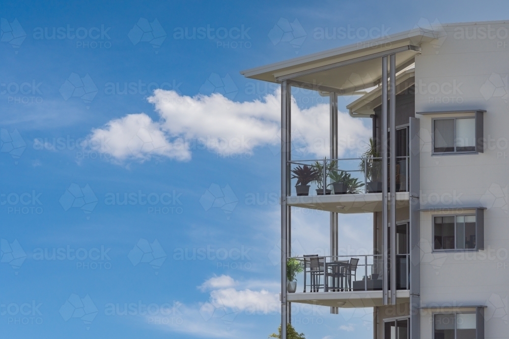 Outdoor balconies of high rise apartments with blue sky and white clouds behind - Australian Stock Image