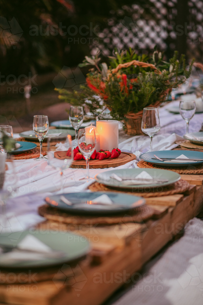 Outdoor dining setup for a festive gathering with candles and flowers at twilight - Australian Stock Image
