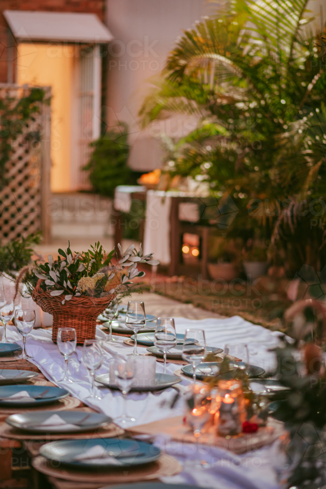 Outdoor dining setup with elegant table arrangement and tropical plants - Australian Stock Image